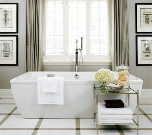 large and formal upscale bathroom with marble tile floor tile, free-standing bathtub, and custom draperies
