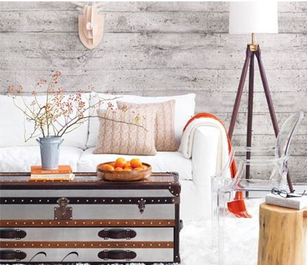 creative light and bright small living room with grey wall treatmet, cream sofa, and antique trunk with orange accents