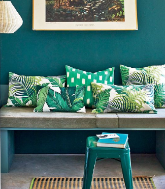 wide view of charming setee in small casual Boho living room with pile of cheerful green and white toss cushions