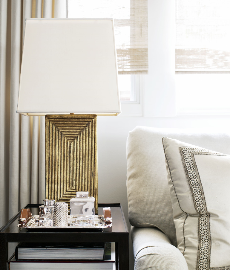elegant white living room vignette with gold table lamp, custom semi-sheer window shades, and toss cushion with banding trim