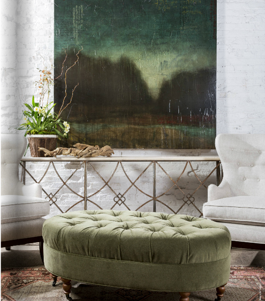 upscale formal living room with tufted white wing chairs, oval tufted ottoman in sage green, and blurred colourful landscape artwork
