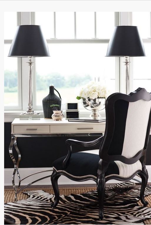 upscale home office in black and white with paired black lamps, black and white bergere chair and zebra area carpet