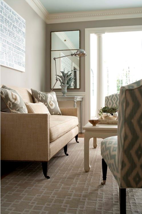relaxed living room with nail studded linen sofa with castors, sand and cream geometric area carpet, aqua and cream paired armchairs, and grey wall colour