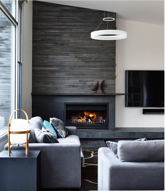 upscale casual living room in masculine colour palette with contemporary stone clad fireplace with adjacent flat screen television