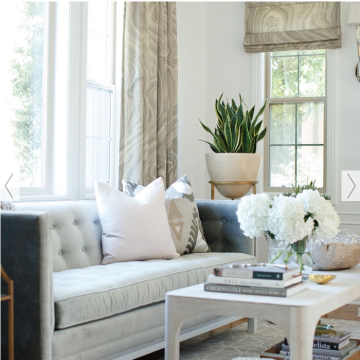 upscale casual living room with button tufted square arm sofa, swirl motif custom draperies and Roman shades, white coffee table and wall colour