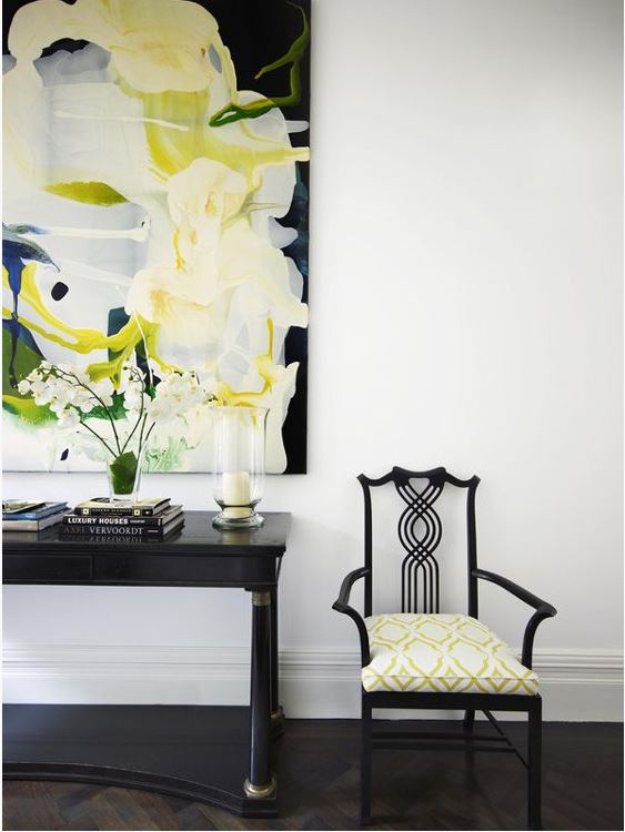 white room with black console table and chair with dark herringbone hardwood floor and large colourful abstract artwork
