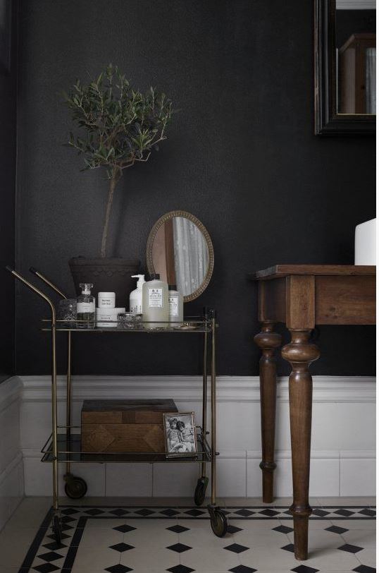 beautiful bathroom with dark wall colour, wooden table vanity with vessel sink, and tea wagon storage for toiletries