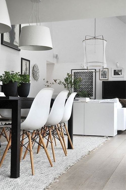 contemporary casual living room and dining room with white dining chairs, black table, white sofa, lighting and wall colour, and black and white artwork