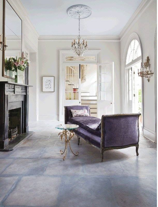 dramatic purple daybed with French styling beside simple fireplace with large mirror over it