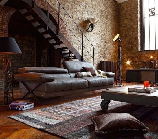 industrial style loft condo living room with distressed leather sofa, muted area rug, wheeled coffee table, and black floor lamp