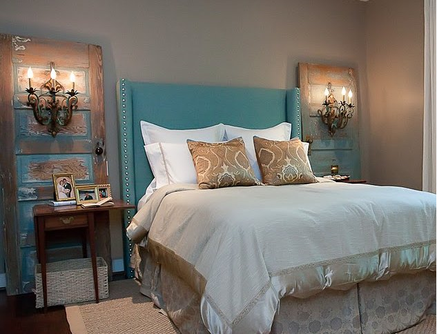 comfortable rustic bedroom with upholstered headboard and ornate sconces on paired weathered doors in turquoise