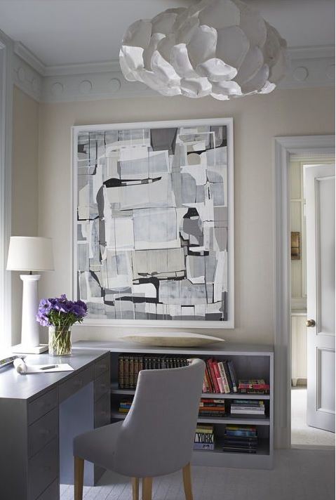 elegant home office corner of living room with light grey storage furniture. artistic light fixture, and large grey abstract artwork