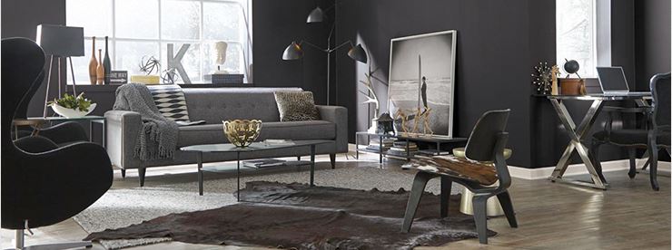 urban loft style living room with black wall colour, tufted grey sofa, paired egg chairs, cow hide rug and chair seat, funky lighting, and chrome x base table