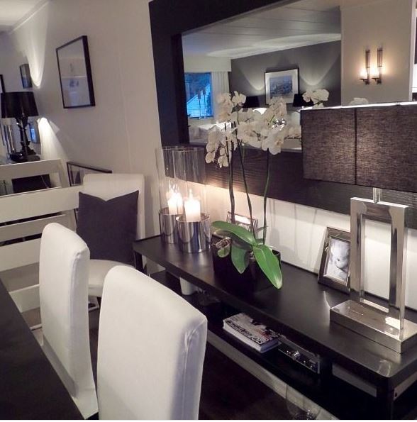 dining room with white chairs, dark table, and console with contemporary square lamp and wide framed mirror