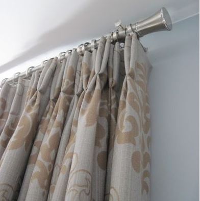 classic custom draperies in neutral fabric with pleated heading on metal decorative rod and rings
