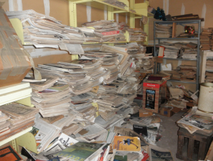 excess unsorted paper clutter on shelves in a small home office