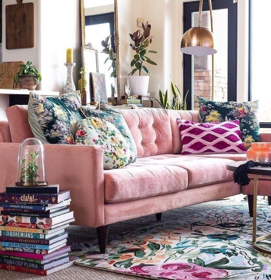 Bohemian living room with tufted pink velvet sofa, floral area rug and brass lighting