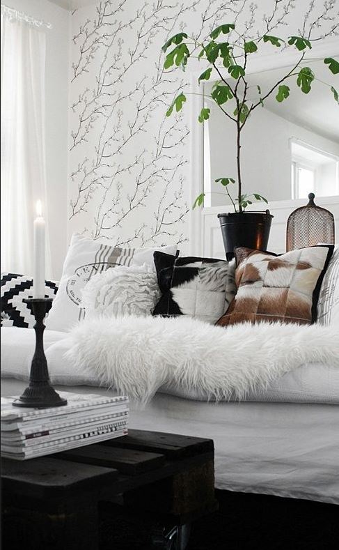black and white living room with black palette coffee table, cow hide cushions, and sketched branch wall mural