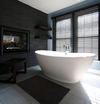 dramatic contemporary bathroom with free-standing tub and black stone wall, and black wood venetian blind