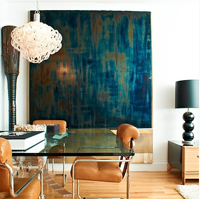 large abstract artwork complements other furnishings in an eclectic dining room