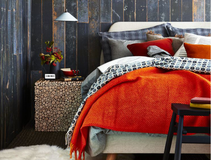 dynamic casual bedroom with dark grey rusticated wood panelling and bright orange-red bedding