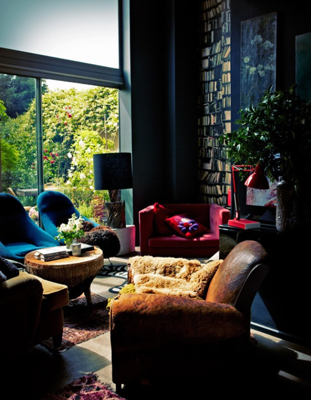 charming funky small living room with black wall colour, tall black built-in bookcase, and Bohemian style weathered distressed leather armchair