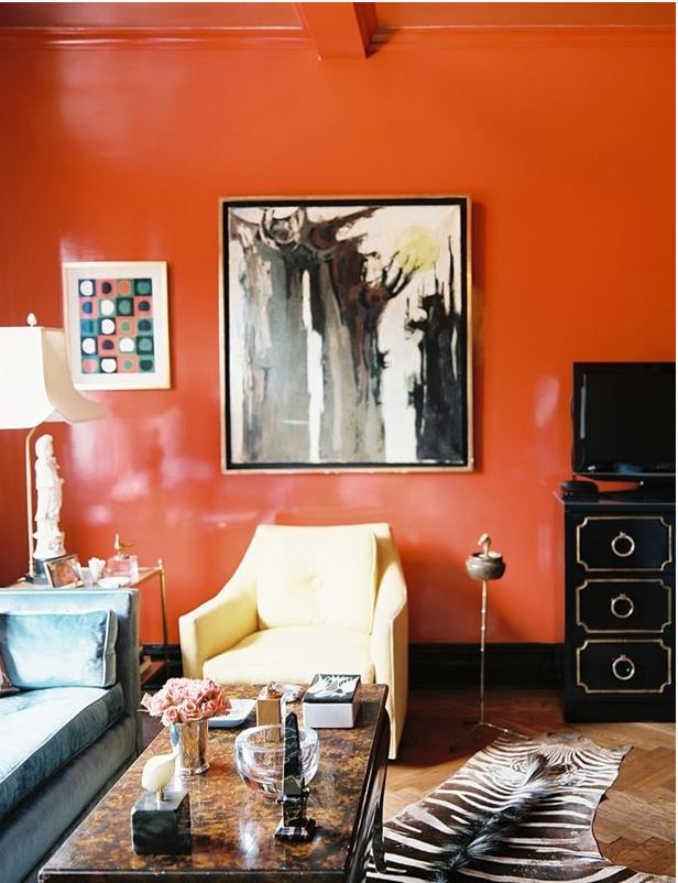 striking living room with zebra area rug, burlwood coffee table, large abstract artork, and glossy orange walls and ceiling