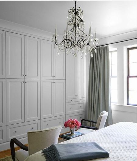 Upscale white bedroom with storage wall and crystal chandelier
