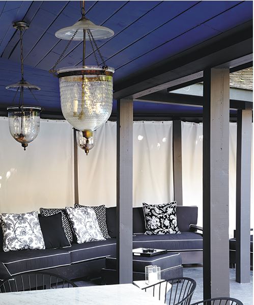 casual upscale outdoor siting area in an open porch with blue ceiling, lanterns, and toss cushions