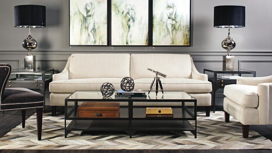 upscale casual living room with herringbone patch hide area carpet, paired silver lamps with black shades, cream slope arm sofa, and tryptich of nudes artwork