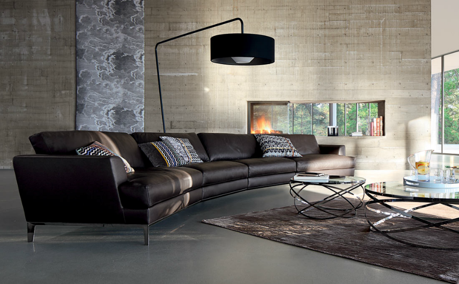 upscale contemporary living room with gently curving long leather sofa, over-hanging floor lamp, and metal and glass coffee tables