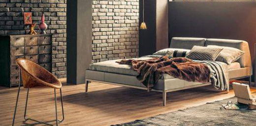 wide view of casual upscale loft condo apartment bedroom with exposed brick, leather chair and faux fur throw