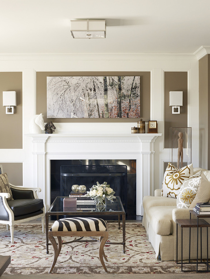 transitional style living room with classic fireplace with added moldings, mid brown wall colour, leather and white wood armchair, area rug, and floral toss cushions