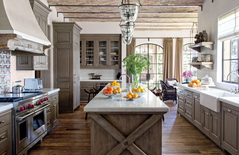 upscale rustic farmhouse style kitchen with weathered finish on island, glass lantern lighting, and ceiling beams