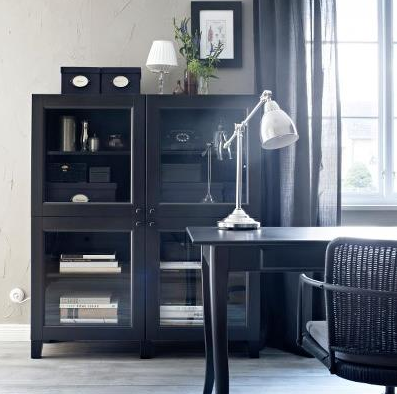 black storage cabinets with glass doors in home office with black table and chair and black gauze draperies